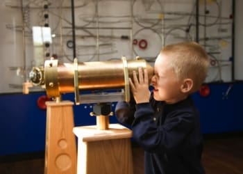 Boy looking through telescope at museum