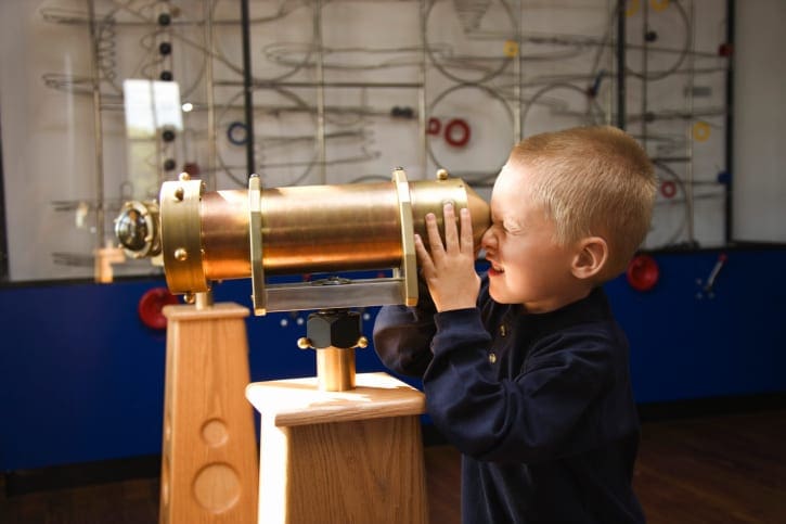 Boy looking through telescope at museum