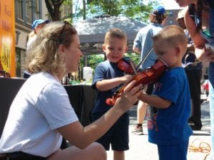 A pair of young musicians take their first violin lessons during Troy River Fest on Saturday, June 18.