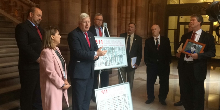 Holding a framed photograph of his son, Michael Carey, with legislators and advocates, listen to Assemblyman Michael Kearns talk about the difficulties inherent in caring for a disabled loved one, and the constant concern for their safety. (Photo by Ali Hibbs/Spotlight News)