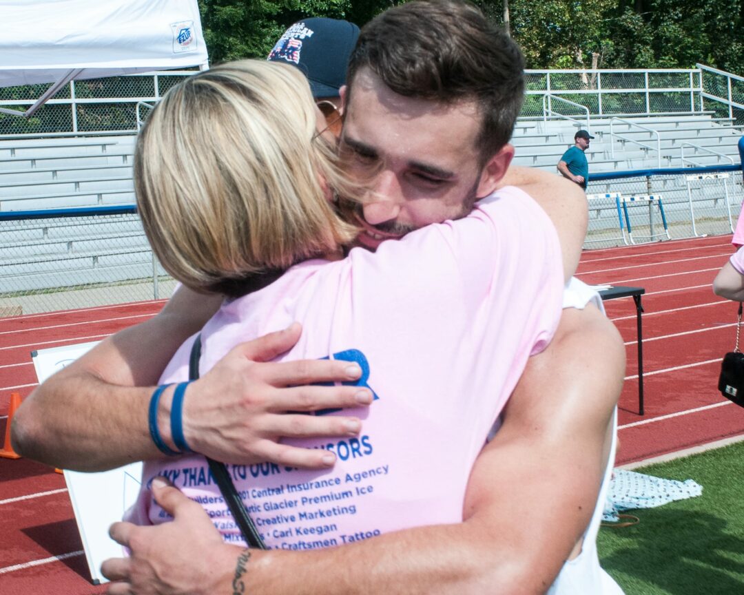 Alicia DiNovo embraces her son Michael before a charity flag football tournament held at Schenectady High School on Sunday, Aug. 13. It was the first time the two were home together since Niko DiNovo’s automobile accident in October 2016.
(Photo by Jim Franco/ Spotlight News)