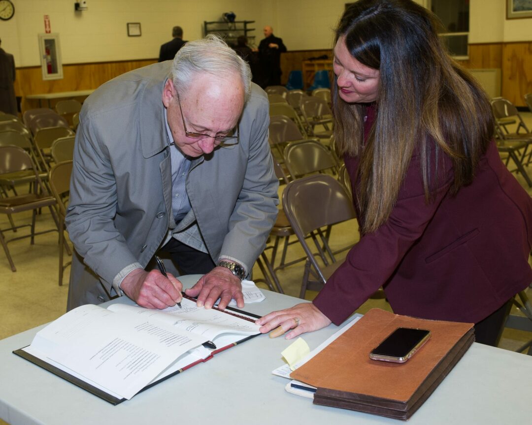 Frederick Ashworth signs the oath book in front of Town Clerk Julie Gansle (Jim Franco / Spotlight News)