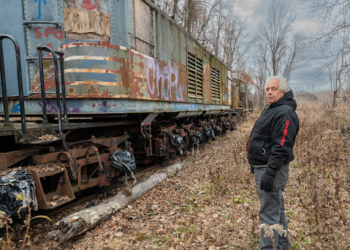 Glenmont resident and train enthusiast Paul Marsh stands by the Alco/GE T-3a locomotive in December 2021 on Beacon Island in Glenmont. Marsh has spent the last 30 years trying to find a way to move the last remaining electric motor of its class to the Danbury rail museum that owns it before the site becomes a factory for wind turbines. (Jim Franco/Spotlight News)