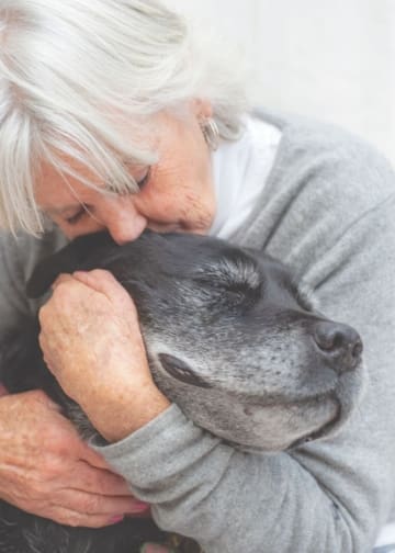 Elderly woman hugs her very old dog.